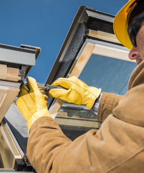 A man in a yellow hat and yellow gloves working on a window